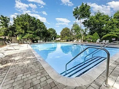 A swimming pool surrounded by trees and a metal ladder.