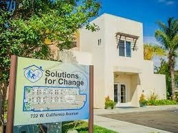 A sign for "Solutions for Change" is in front of a building.