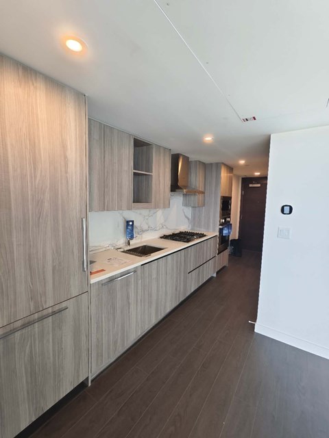 A modern kitchen with wooden cabinets and a marble countertop.