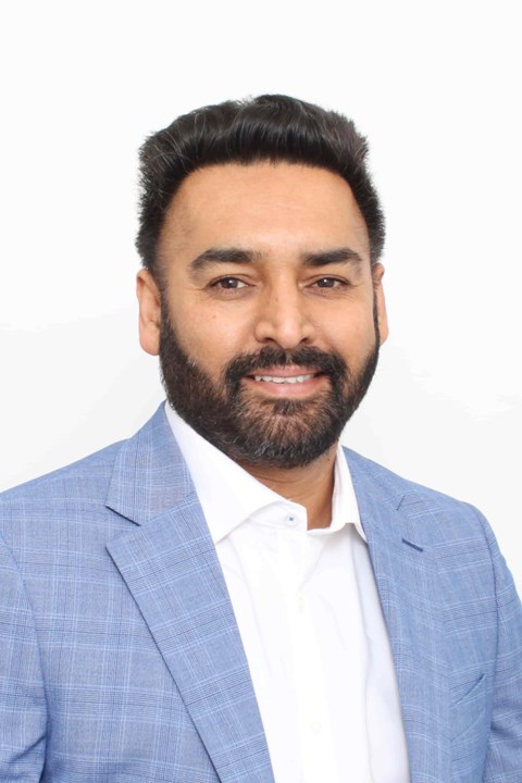A man with a beard wearing a blue checkered blazer.