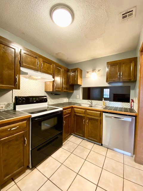 A kitchen with wooden cabinets and a white stove top oven.
