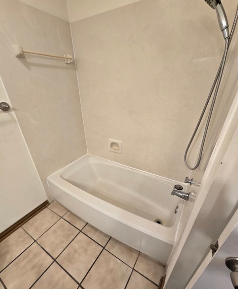 A white bathtub with a shower head and a shower hose.