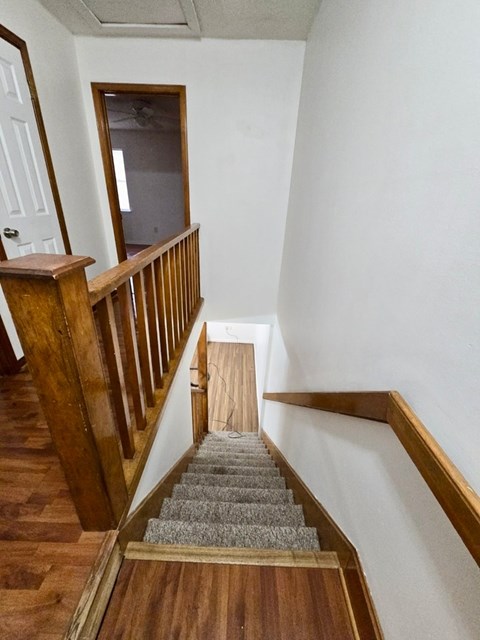 A staircase with wooden railings and a grey carpeted runner.