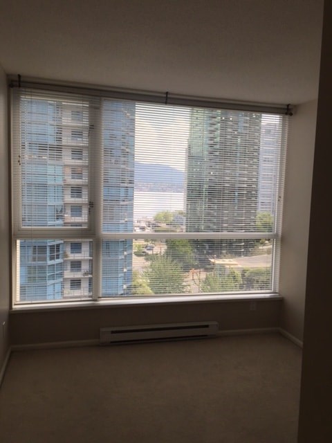A window with blinds overlooking a cityscape.