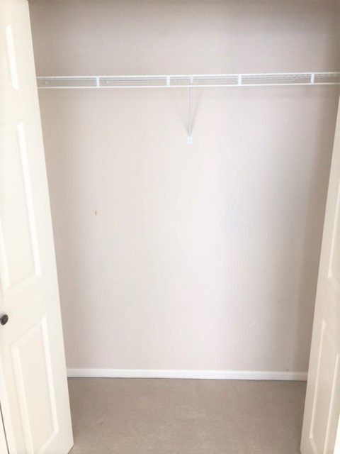 A white door is open to a room with a white wall and a white shelf.