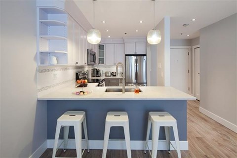 A kitchen with a bar stool in front of the counter.