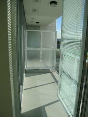 A hallway with a glass wall and a white floor.