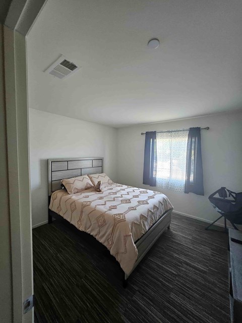 A bedroom with a bed, chair, and window.