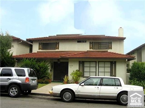 A white car is parked in front of a house.