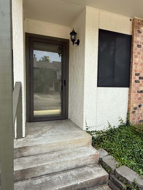 A glass door is on the left side of a white wall.