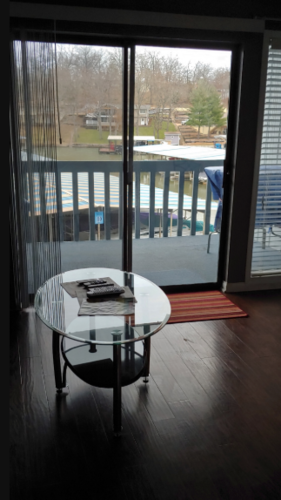 A glass table with a book on it in front of a sliding glass door.