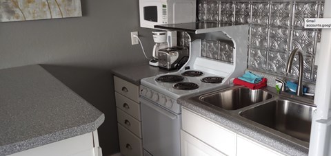 A kitchen with a white stove top oven and a silver sink.