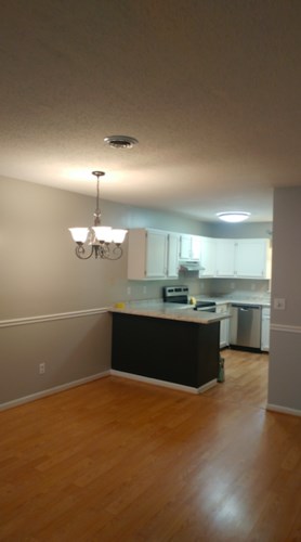 A kitchen with a black counter and a chandelier.