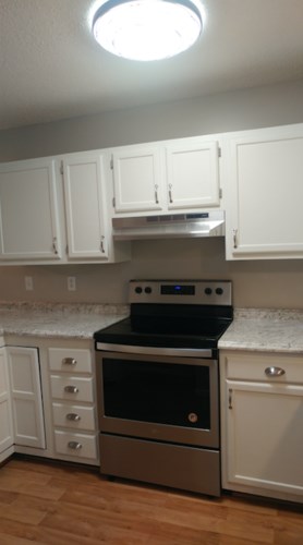 A kitchen with a stove top oven and white cabinets.