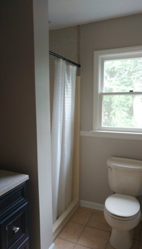 A white toilet sits in a bathroom next to a window.
