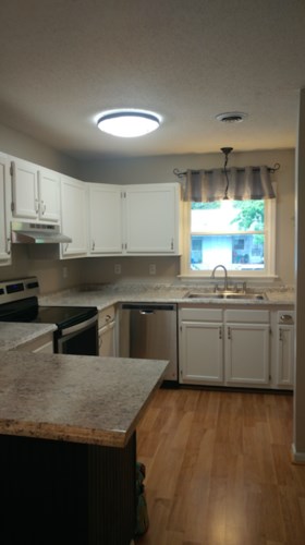 A kitchen with white cabinets and a granite counter.