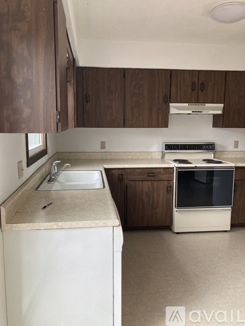 A kitchen with a white dishwasher and brown cabinets.