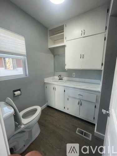 A bathroom with a toilet, sink, and cabinets.