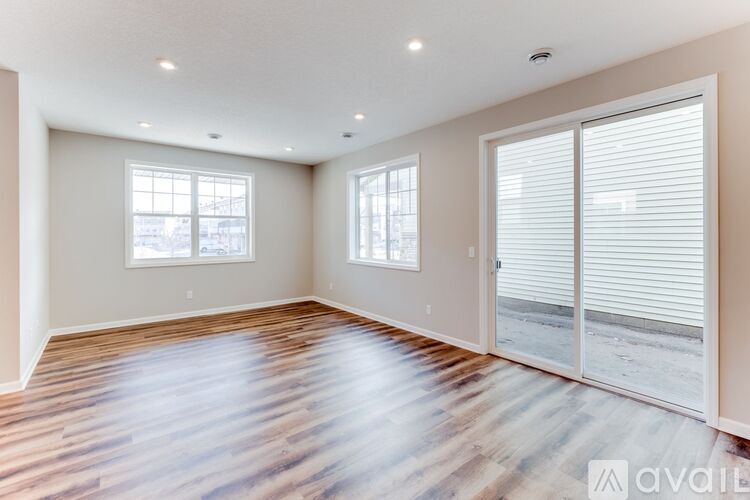 A spacious room with wooden floors and two windows.