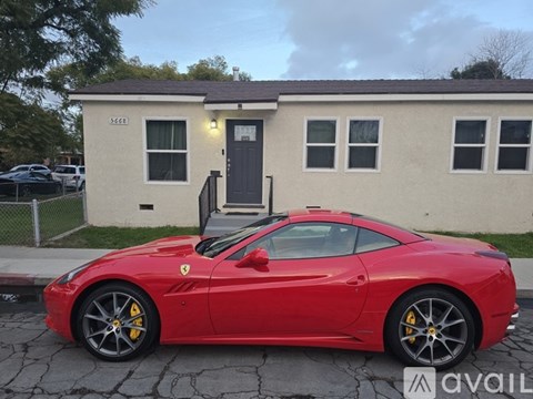 A red Ferrari is parked in front of a small house.