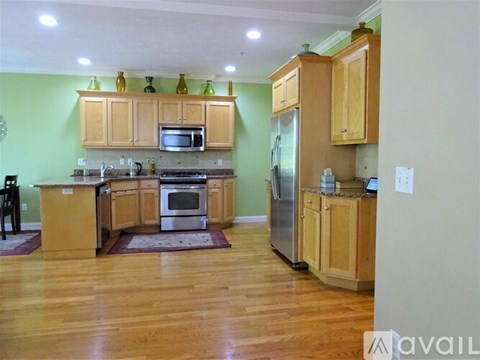 A kitchen with wooden cabinets and a green wall.
