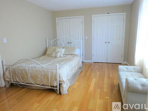 A bedroom with a white bed and a white couch.