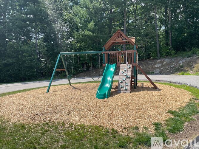 A playground with a green slide and a wooden structure.