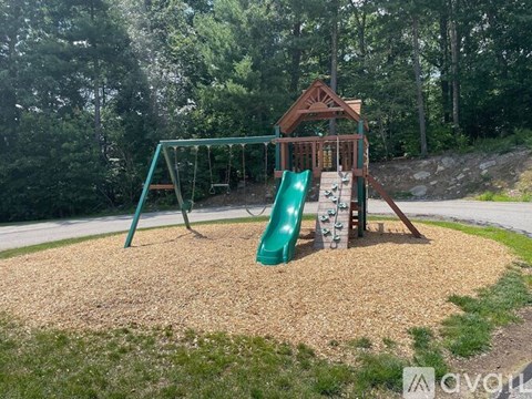 A playground with a green slide and a wooden structure.