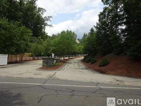 A road with a white fence and trees on both sides.