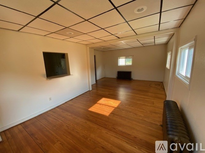 A room with wooden floors and a flat screen TV mounted on the wall.