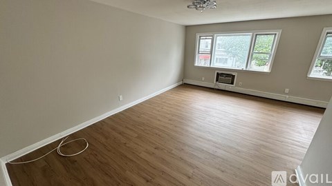 A room with wooden flooring and a window showing a view of a building outside.