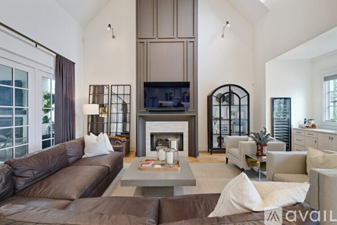 A living room with a brown leather couch and a fireplace.