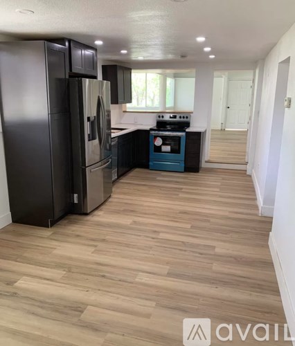 A kitchen with black appliances and wooden floors.