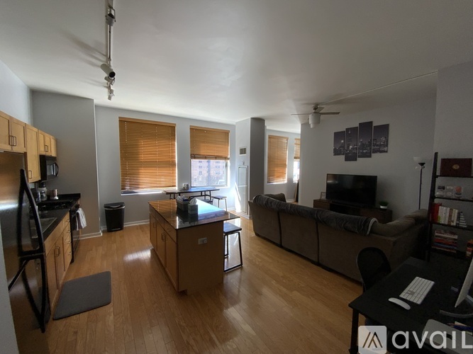 A living room with a couch, a television, and a kitchen area with wooden cabinets and a black countertop.