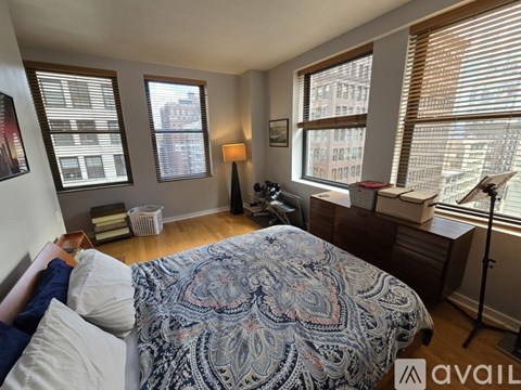 A bedroom with a bed in the center and a window with blinds on the right.