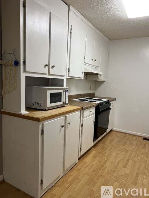A kitchen with white cabinets and a wooden counter top.