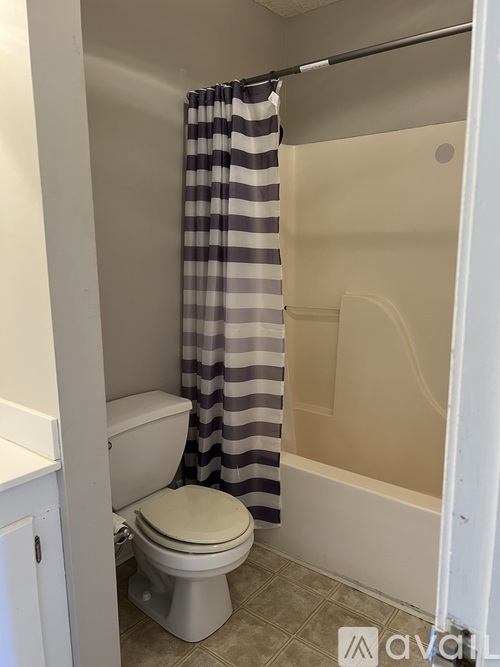 A white toilet with a striped curtain in a bathroom.