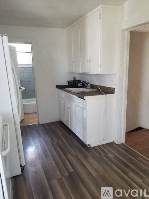A kitchen with white cabinets and a refrigerator.