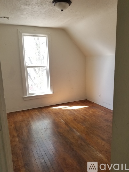 A room with a window and wooden floors.