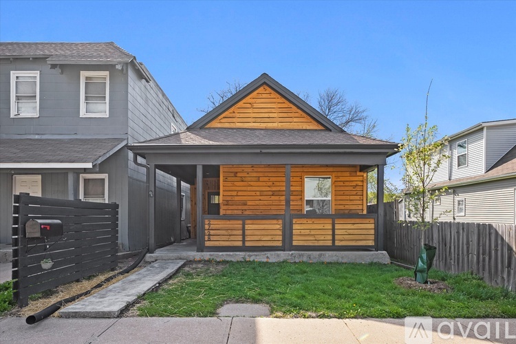 A house with a wooden front door and a grey house in the background.