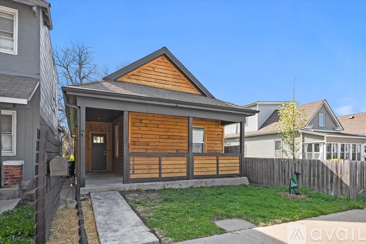 A wooden house with a porch and a fence in front of it.