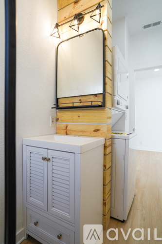 A mirror is mounted on a wooden shelf above a white cabinet.