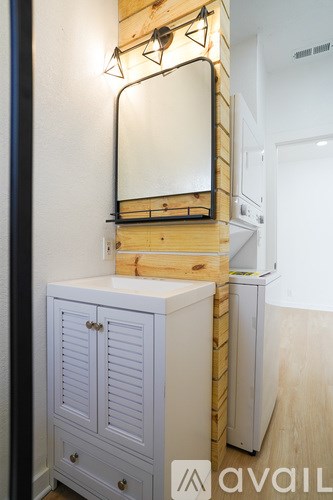 A mirror is mounted on a wooden shelf above a white cabinet.