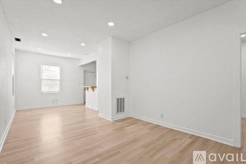 A spacious room with wooden flooring and white walls.