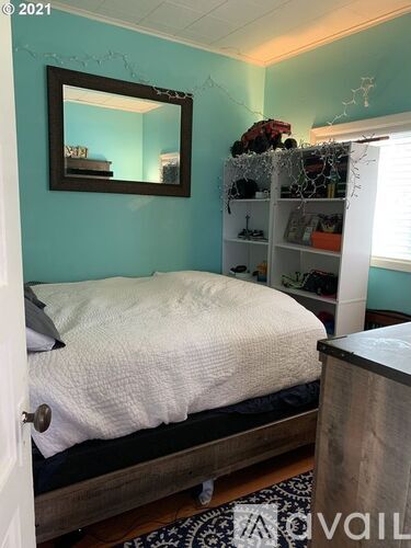 A bedroom with a bed, a mirror, and a shelf with items on it.