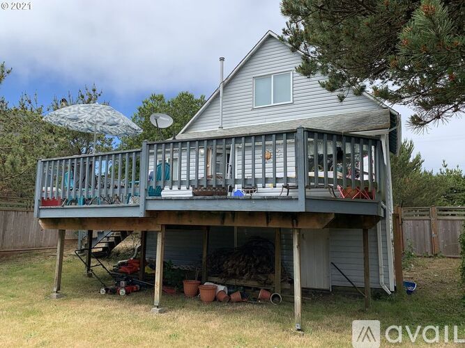 A house with a grey roof and a balcony with chairs and an umbrella.