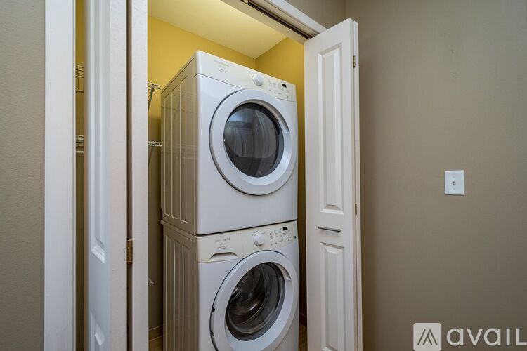 A stack of two white front loading washing machines in a small room.