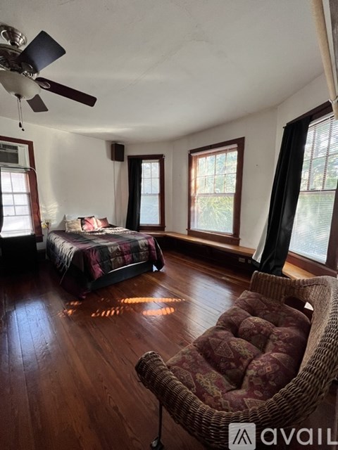 A bedroom with a bed, chair, and ceiling fan.