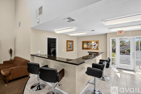 A living room with a brown couch and a bar area with stools.