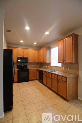 A kitchen with wooden cabinets and a black fridge.